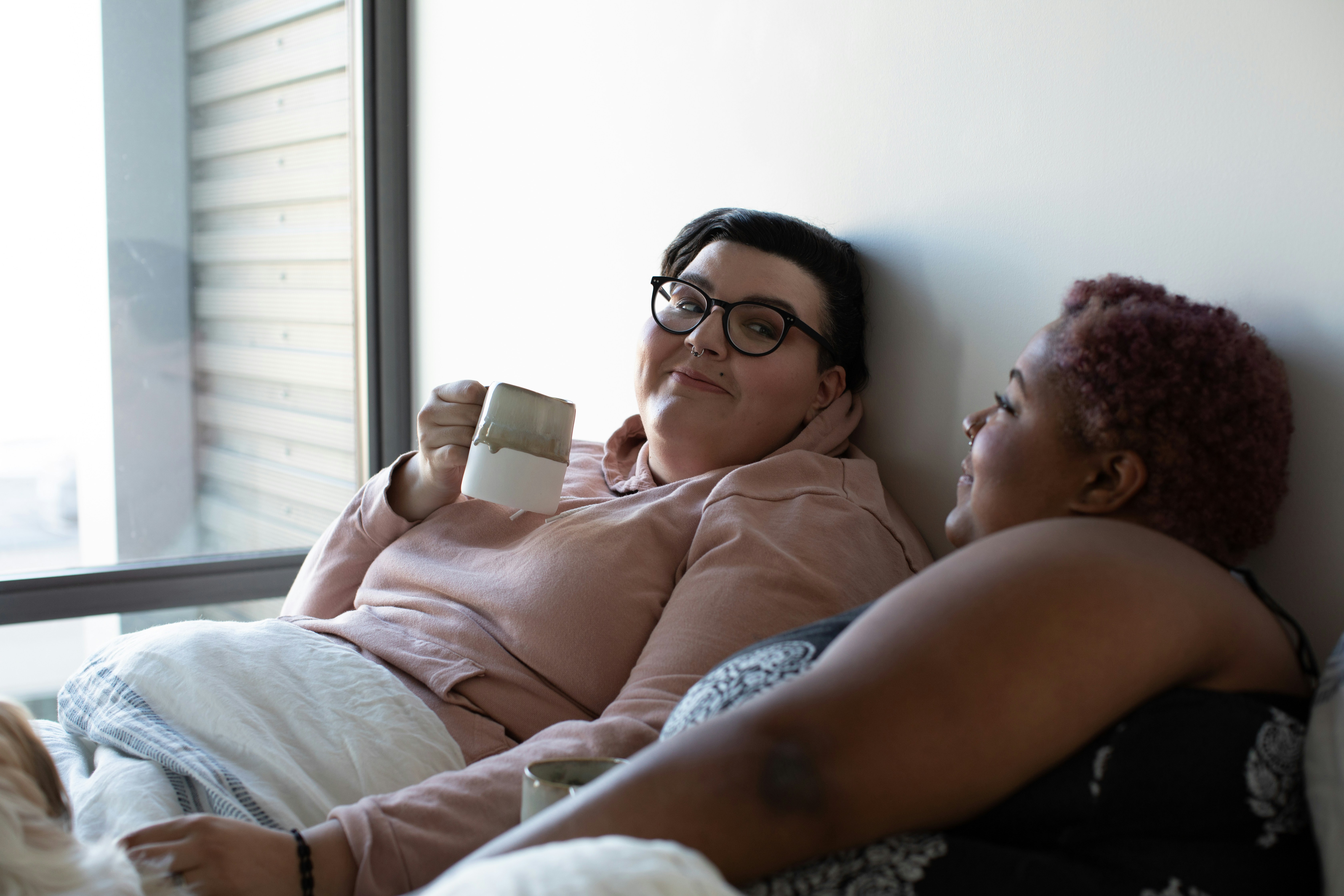 Two women relaxing together on a couch, laughing