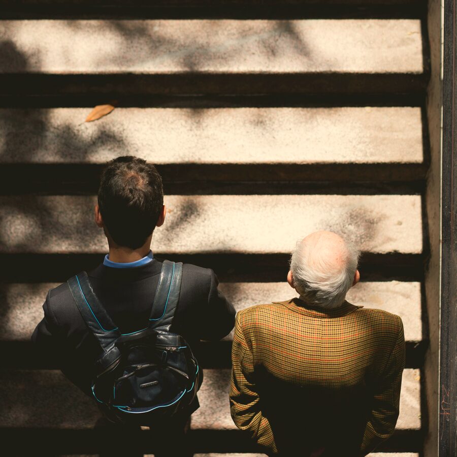 A younger man and an older man sitting side by side on a set of steps