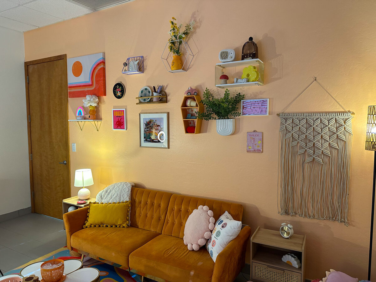 The waiting space — a mustard velvet couch beneath a colorful gallery wall
